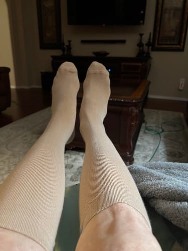 Reviewer relaxing with their legs up, wearing tan Performance Eucalyptus Compression Socks in a living room.