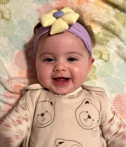 Customer's happy baby wearing the Teddy Bear Ultimate Baby Sleep Bag and smiling directly at the camera.