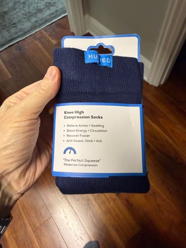 Customer's hand holding the navy Performance Eucalyptus Compression Socks in their packaging.