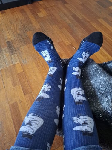 En kunde viser sine ben i de blå Moomin-støttestrømper, mens de sidder ned.