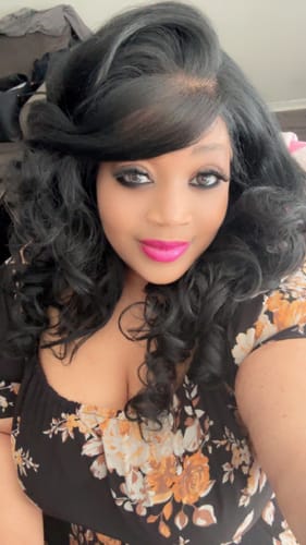 Close-up of a customer wearing a styled black wig with soft, bouncy curls.