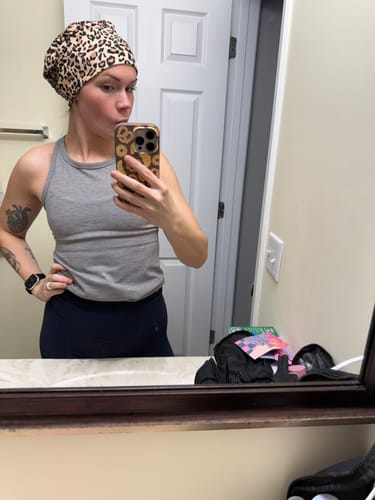 Customer wearing the DuoStyle Scrub Hat in a cheetah print, taking a mirror selfie.