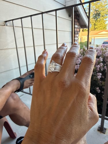 A reviewer's hand wearing the white silicone ring, highlighting the large stone.