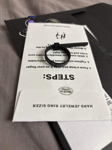 Customer's black Ring Sizer resting on its white packaging with instructions.