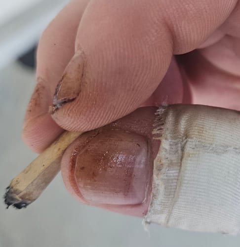 Close-up of a customer holding a lit joint made from the Roll Ready Ground Hybrid Flower.