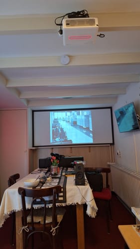 De beamer van de klant, gemonteerd aan het plafond, projecteert een film op een scherm in een kamer.