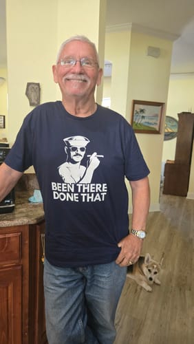 Customer smiling while wearing the navy 'Been There, Done That' Everyday Tee in a home setting.
