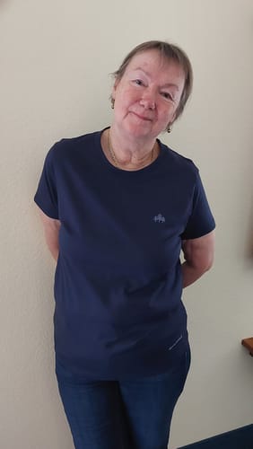 Eine Rezensentin trägt das gut sitzende, dunkelblaue Bio-Damenshirt und zeigt dessen Passform an Schultern und Hüfte.