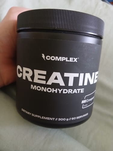 Customer holding a black tub of Complex Creatine Monohydrate supplement.