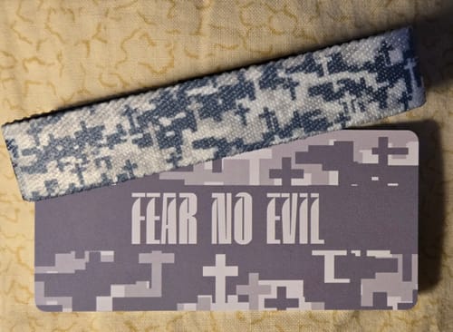 Customer's Fear No Evil bracelet with a digital camouflage design made of crosses, resting on its 'FEAR NO EVIL' card.