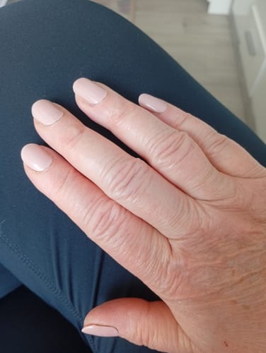 Hand einer Kundin mit den dezenten UV Gel Nail Wraps 'Whipped Latte' auf den Nägeln.