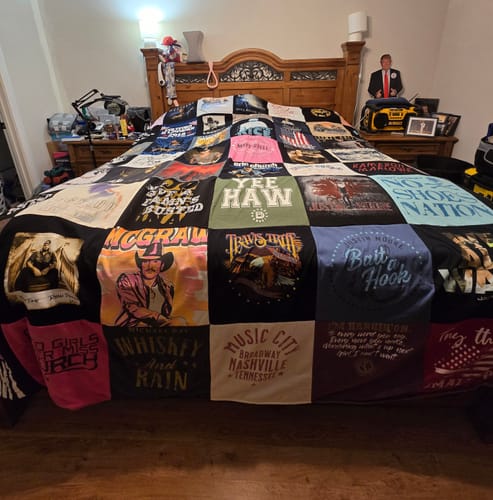 Customer's large T-Shirt Quilt with colorful squares spread across a king-size bed, hanging over the edges.