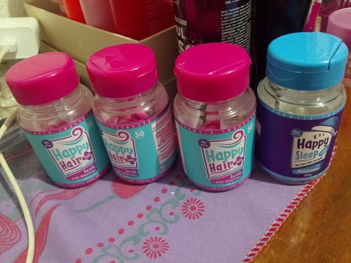 Cliente exibe os três potes do suplemento Happy Hair e um pote de Happy Sleep do kit.