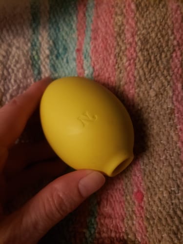 Close-up of a reviewer holding the yellow, lemon-shaped Lem Clitoral Massager in their hand.