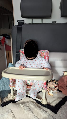 Reviewer's baby sitting in the floral-patterned Paloma baby chair with its attached cream tray.