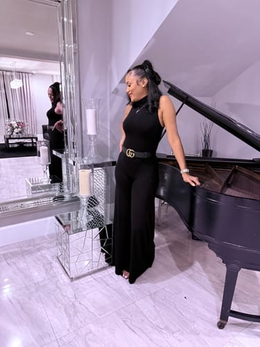 Reviewer standing in a living room wearing the sleek, black NW Turtleneck Wide Leg Jumpsuit, showing its long fit.