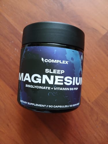 Customer's black jar of Complex Sleep Magnesium supplement sitting on a wooden surface.
