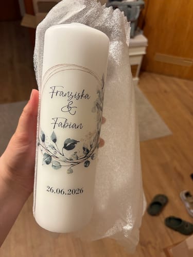 Rezensent hält die große, personalisierte Traukerze 'Floral Kreis' mit Namen und Datum nach dem Auspacken in der Hand.