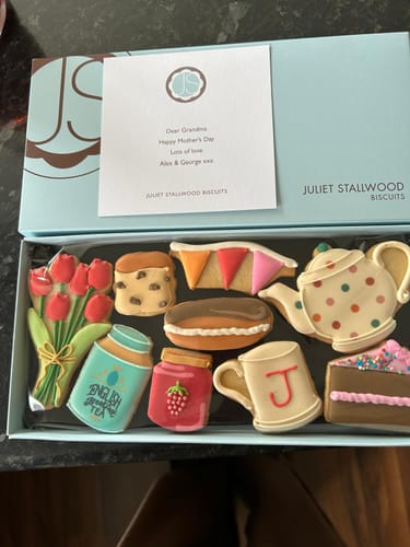 Customer's open Mother's Day Tea Deluxe Biscuit Box, showing the nine assorted, decorative biscuits and a personalized note inside.