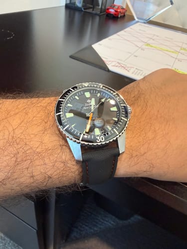 Customer's wrist wearing a dive watch with the black Sailcloth Rubber Deploy strap with red stitching.