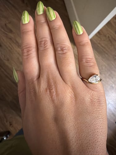 Reviewer's hand wearing the Pia Ring, showing the sparkly pear-cut stone and gold wave band.