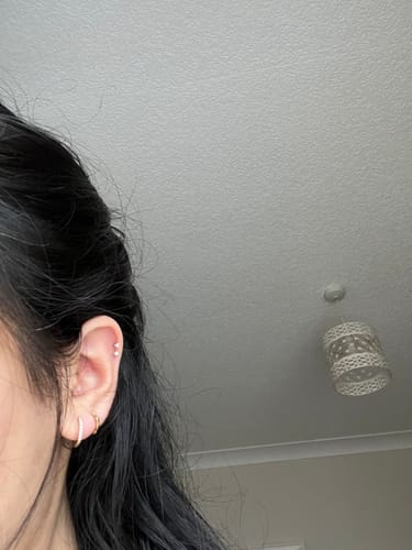 Reviewer showing the gold Bamboo Huggies worn in their second lobe piercing.