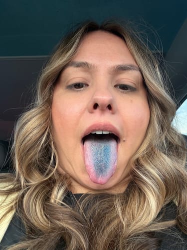 Close-up of a reviewer sticking out their tongue, which is stained blue after using Just Blue™.