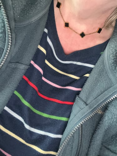 Customer wearing the Celine Ten Clover Necklace with delicate, black clover-shaped charms around their neck.