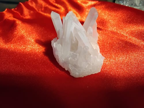 Customer's white Crystal Quartz Cluster with multiple points on a shiny red fabric.