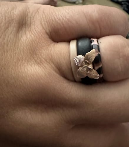 Close-up of a reviewer's hand wearing the Butterfly Collection ring stacked with other patterned silicone rings.