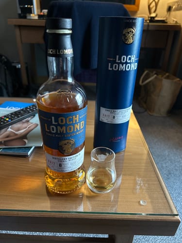 Customer's bottle of Distillery Edition Ten Single Malt whisky, its blue packaging, and a poured tasting glass on a table.