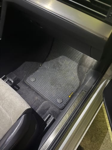 Klient pokazuje idealne dopasowanie szarego dywanika samochodowego w swoim aucie.