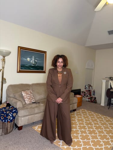 Reviewer standing in a living room wearing the brown Power Shoulder Fitted Suit Blazer and matching wide-leg pants.