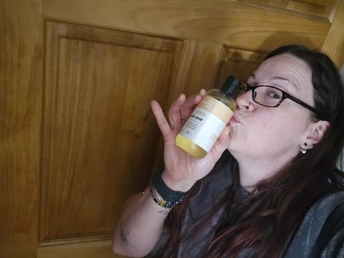 Reviewer happily kissing her bottle of Body Splash Skin Smoothing Body Oil.