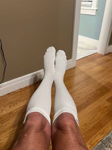 Customer relaxing with feet up, wearing the white Performance Eucalyptus Compression Socks.