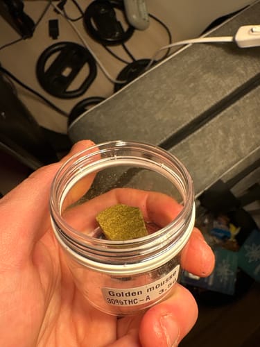 Customer holding a small clear jar containing a golden-brown block of Golden Mousse.