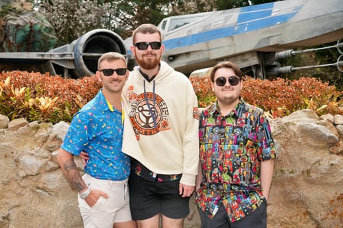 Customer in a bright 'Deep (Space) Trouble' polo, standing with two other people outdoors.