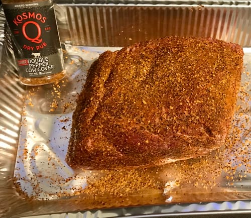 Customer's raw meat generously coated in Double Pepper COARSE Cow Cover Rub in a foil pan before cooking.