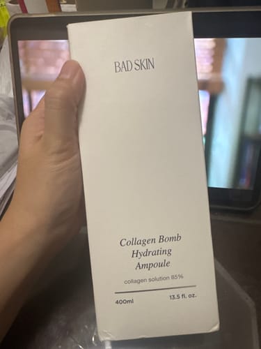 Customer holding the white box of the Bad Skin Collagen Bomb Hydrating Ampoule.