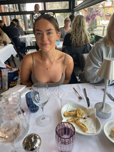 Customer's granddaughter wearing the gold Magnetic Love Necklace while seated at a restaurant.