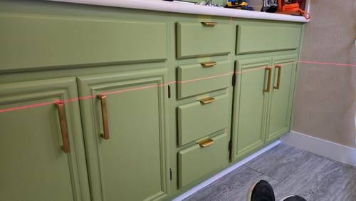 Customer's light green cabinets being installed, showing the smooth finish of the DECOGLO® paint.
