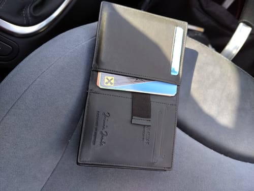 Reviewer's open black Slimstar wallet with several cards inside, resting on a gray car seat.