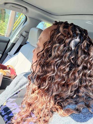 Reviewer from the side showing their loose deep wave crochet hair styled with small braids in a color blend.