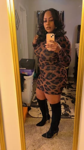 Reviewer takes a mirror selfie wearing the long-sleeved, leopard print Naked Print Mini Dress.