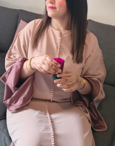 Reviewer sitting on a couch wearing the elegant Nayla Pink kaftan, showing the fit and refined embroidery details.
