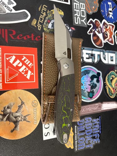 Customer's Tuya Seaxy folding knife shown open, highlighting its green and black Hulk Camo Carbon handle on a leather sheath.