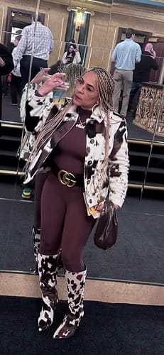 Reviewer wearing the brown form-fitting Naked Closed Toe Jumpsuit, styled with a cow-print jacket and boots.
