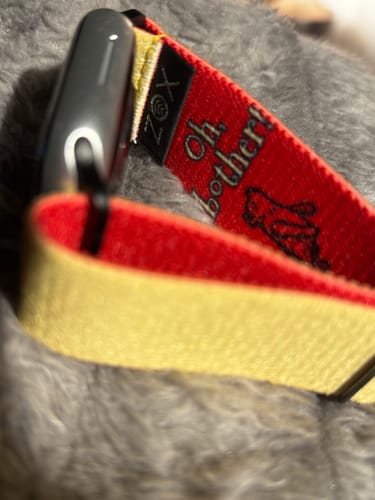Close-up of Reviewer's red Winnie The Pooh watch strap attached to a watch, showing the text 'Oh, bother!'.