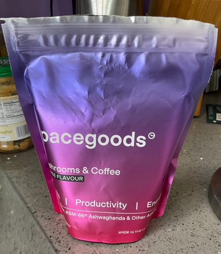 Customer's purple and pink bag of Rainbow Dust, a mushroom and coffee drink mix, resting on a counter.