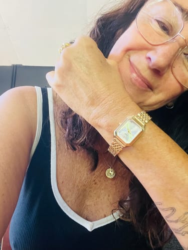 A reviewer wearing the stylish, gold-toned CLAIRE DE MAINS watch on their wrist.